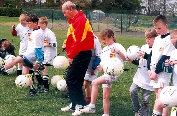 Sir Bobby Charlton gives tips to youngsters on Bullocksteads Sports Ground in May 1996 in