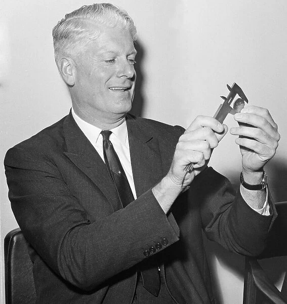 Sir Hugh Conway measuring the new fifty pence piece after it was unveilled at a press