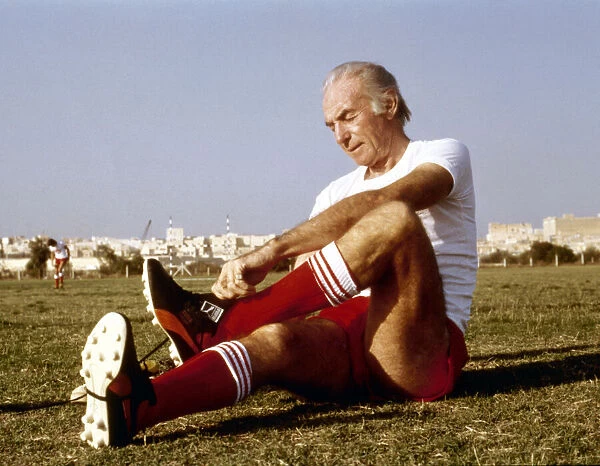 Sir Stanley Matthews puts on his football boots before taking part in agame in Malta