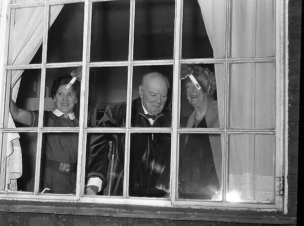 Sir Winston Churchill MP stands looking out of a window with his wife
