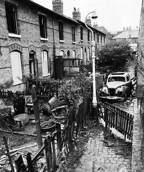 Slum housing in Birmingham. Burnt out car in the alleyway behind derelict houses