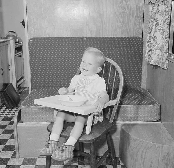 Small boy in high chair enjoying his lunch Circa 1959