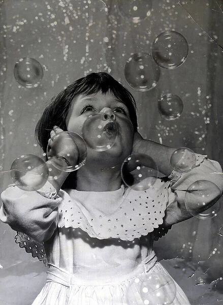 Small girl fascinated by the bubble machine at the 1959 Toy Fair This is a