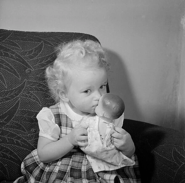 A small girl plays with her doll Circa 1957