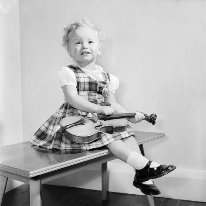 Framed Print : Small girl reading her book also seen with her dolls and violin. 1955 A138 Framed Print : Small girl reading her book also seen with her dolls and violin. 1955 A138