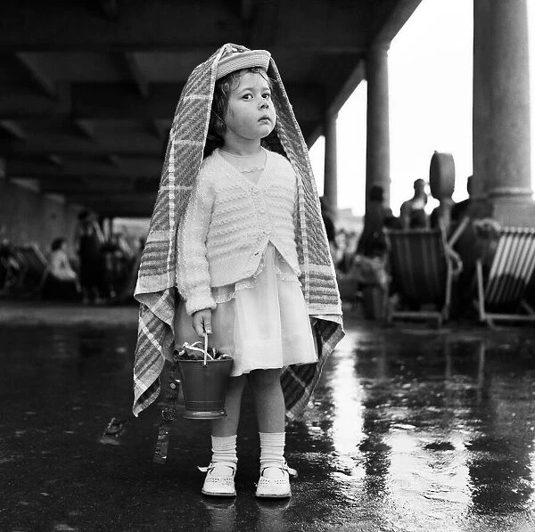 A small girl sheltering from the rain at Barry Island, Vale of Glamorgan, Wales
