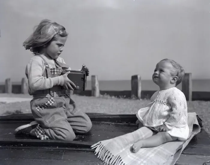 Framed Print : A small girl takes a picture of her little sister on Brighton beach whilst enjoying