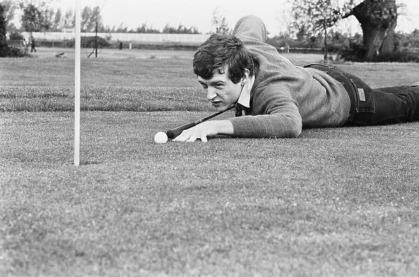 Snooker player Steve Davis on a golf course putting with a cue. 8th June 1981