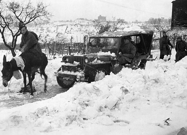 Snow falls on the 8th Army front. British troops clear the main route forward