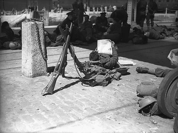 A soldier relaxing reading his Daily Mirror newspaper following his evacuation along with