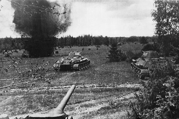 Soviet heavy tanks headed for a firing position advancing across flat wooded countryside