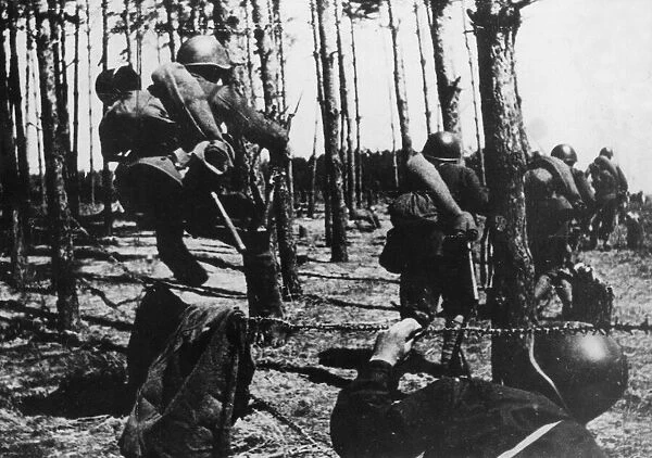 Soviet Red Army troops picking their way carefully through Nazi defence wire as they