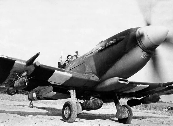 A Spitfire IX fighter plane fitted with three bombs ready to take off in Normandy