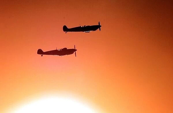 A Spitfire and ME109 (bottom) fly over the war memorial, with a low autumnal sun behind