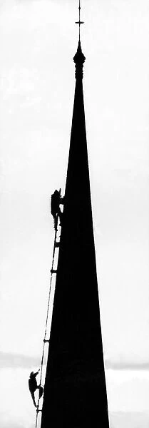 Spotlighted against the wintry city skyline are members of a team of steeplejacks who are
