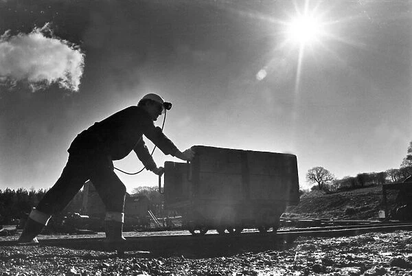 A staff member dressed as a miner pushing a bogie at Beamish Museum