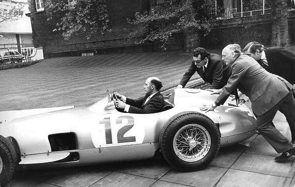 Stirling Moss sitting in his Mercedes racing car being pushed by Lord Montagu - May 1973