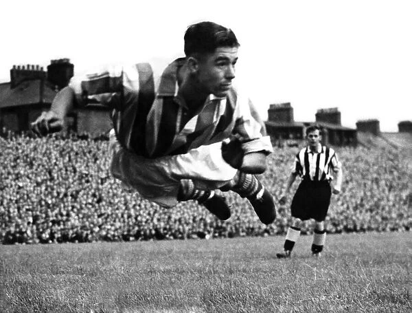Stoke centre-half Frank Mountford diving to head away a George Robledo shot at Newcastle