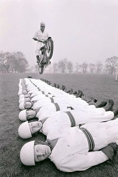 Stunt team in action 1966 Man leaps on a motorcycle over men lying on the ground