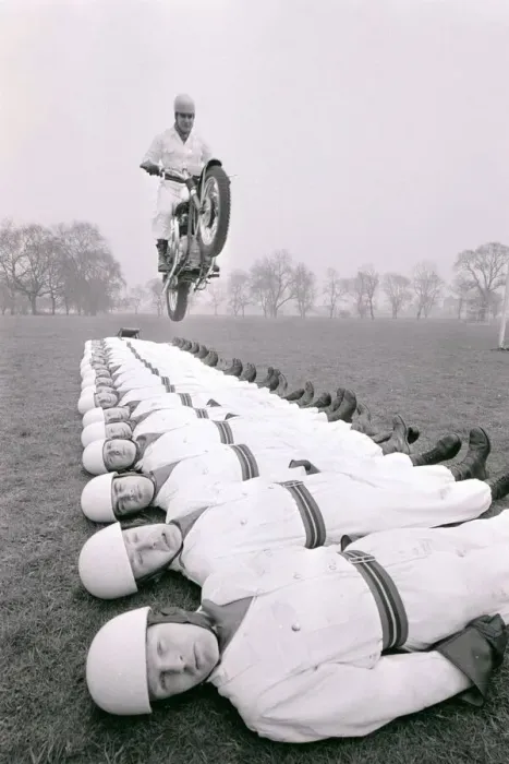 Framed Print : Stunt team in action 1966 Man leaps on a motorcycle over men lying on the ground