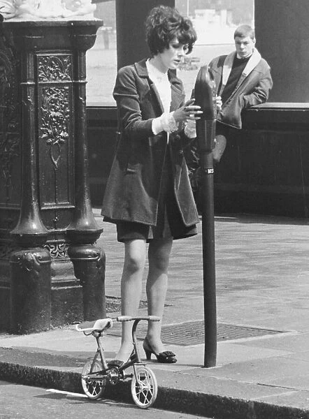 Sue Lloyd actress puts money in a parking meter May 1967 for her mini