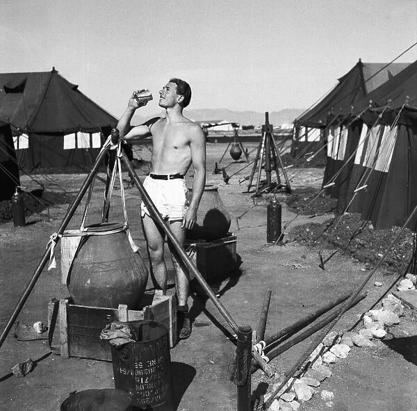 Suez Crisis 1956 A British soldier cools himself down with a drink on an airfield