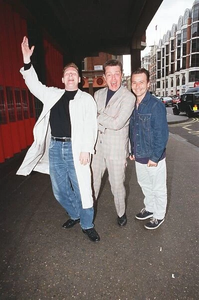 Suggs, lead singer of British ska group Madness, with two members of the group posing for