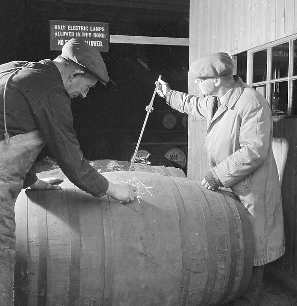 A supervisor at the Glenlivet Distillery measures the contents of barrels of their