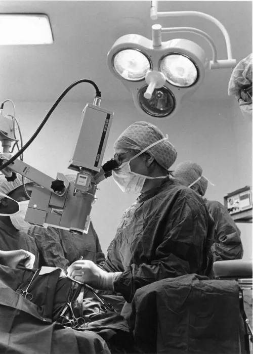 Framed Print : A surgeon looks through the microscope as she works on the patient Framed Print : A surgeon looks through the microscope as she works on the patient