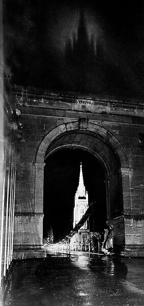 Through the suspension bridge arch under which two girls shelter All Saints Church at