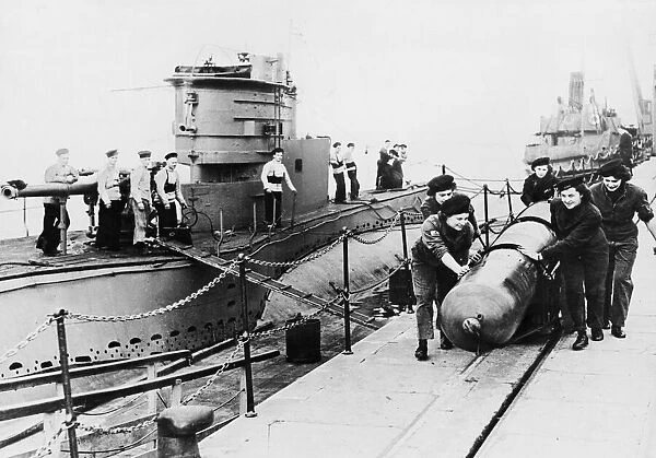 A team of five Wrens wheel a trolley carrying a 21 inch torpedo along the dockside at HMS