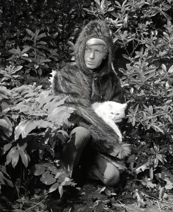 Framed Print : Ted Dawson modelling a fake fur coat with a hood for men while holding a white furry cat Framed Print : Ted Dawson modelling a fake fur coat with a hood for men while holding a white furry cat
