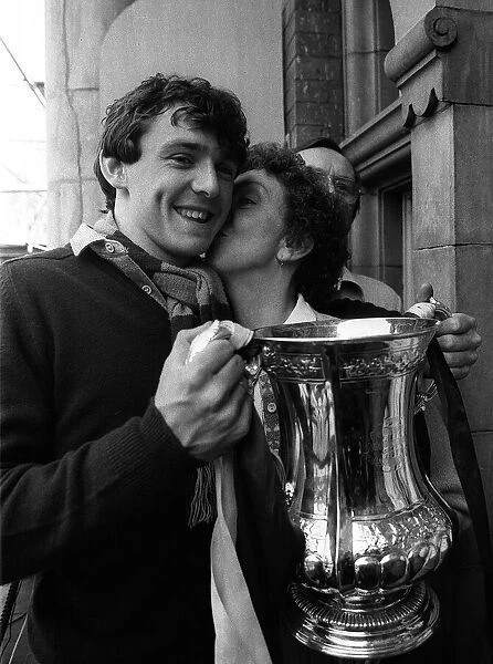 Teenager Paul Allen holds the FA Cup as his mother gives him a kiss on the cheek at
