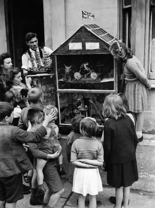 Framed Print : Tom Binnie in apron and his wife placing toy ship model in showcase before one of Framed Print : Tom Binnie in apron and his wife placing toy ship model in showcase before one of