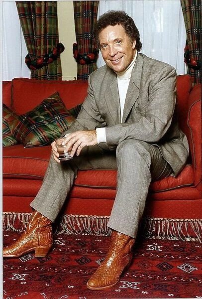 Tom Jones British Singer Sitting on a red couch Holding a glass