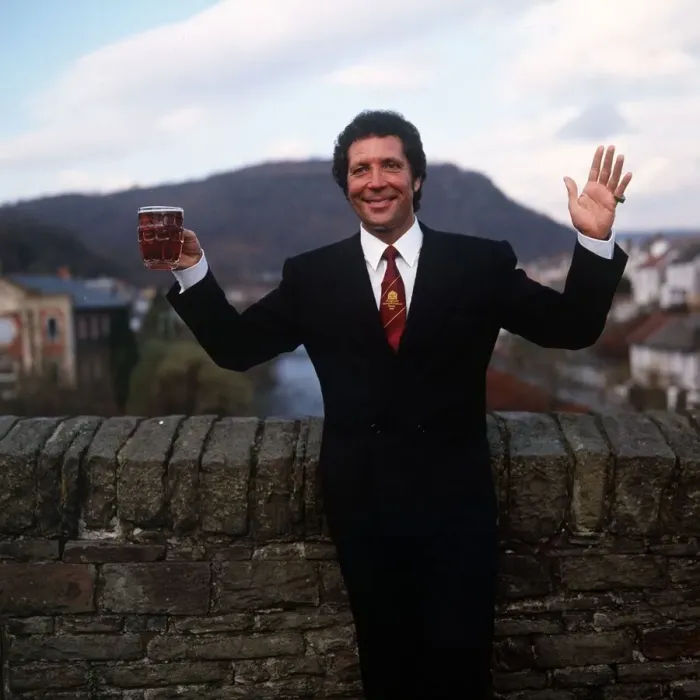 Framed Print : Tom Jones Singer in his home town in Wales standing by brick wall holding pint glass of