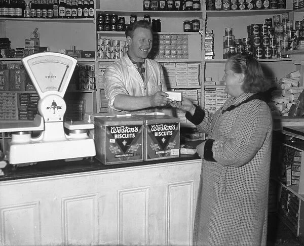 Tom Slinn, cut price grocer, seen here behind the counter serving a customer at his shop