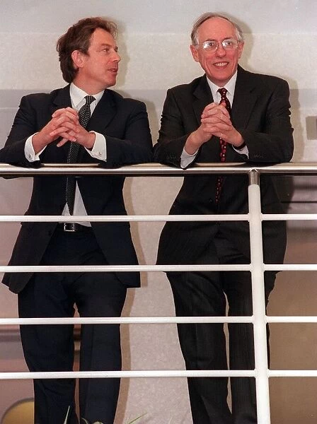 Tony Blair looks sideways at Donald Dewar April 1999 leaning on railings at the new