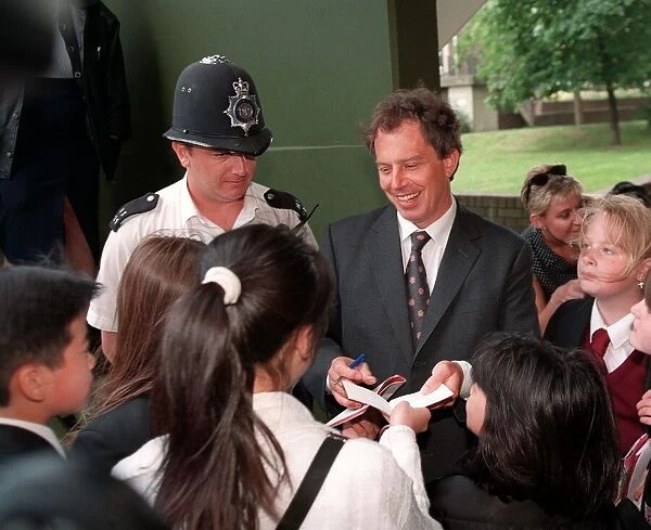 Tony Blair visits a council estate in London June 1997, signing autographs whilst meeting