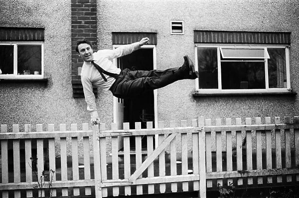 Tottenham Hostpurs footballer Jimmy Greaves leaps over a garden fence, January 1964