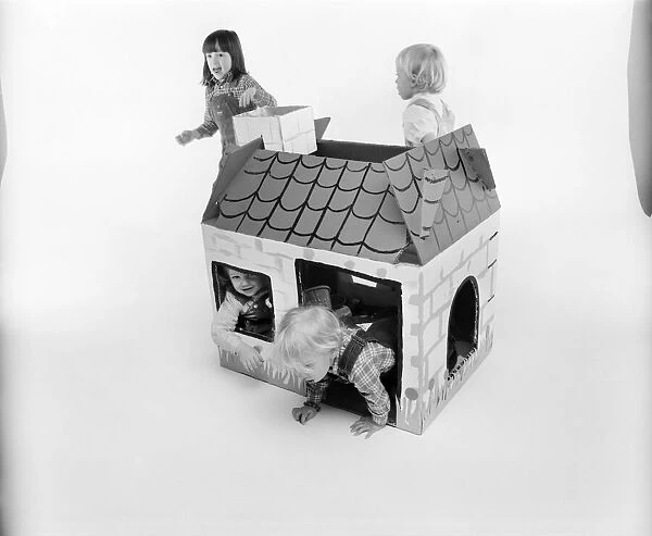 Toys: Children playing with a Wendy house made out of cardboard