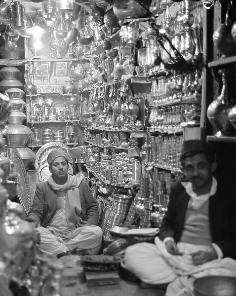 Traders Ironmongers sit inside their shop in Peshawar amongst the pots and pans