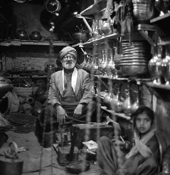 Traders sit inside their shop in Peshawar amongst the pots and pans