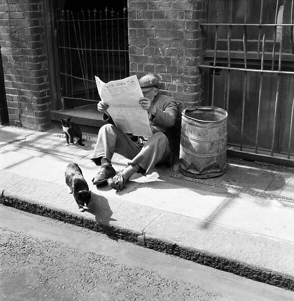 A tramp sitting down on the pavement reading the Financial Times