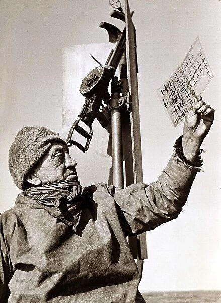 A trawler man on deck, studying an aircraft chart May 1942