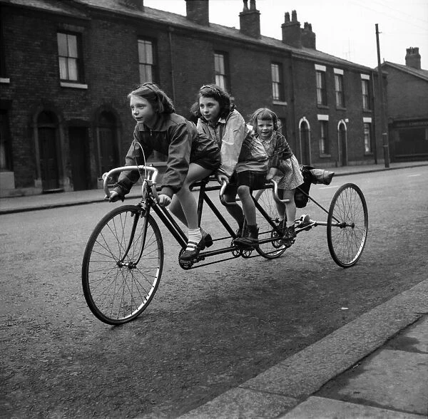 Tricycle For 3 Tom Nolan and family pedalling down their street. November 1952 C5651