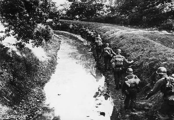 Troops of the 7th Army proceed along a muddy irrigation ditch near Remiremont, France