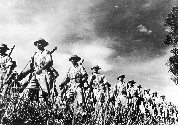 troops of a famous Indian regiment advancing in column through countryside in Malaya