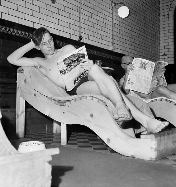 Turkish bath assistant Ernest Smith reading his newspaper. January 1953 D259
