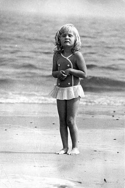 A typical British summer holiday scene, a young girl shivers in the sea